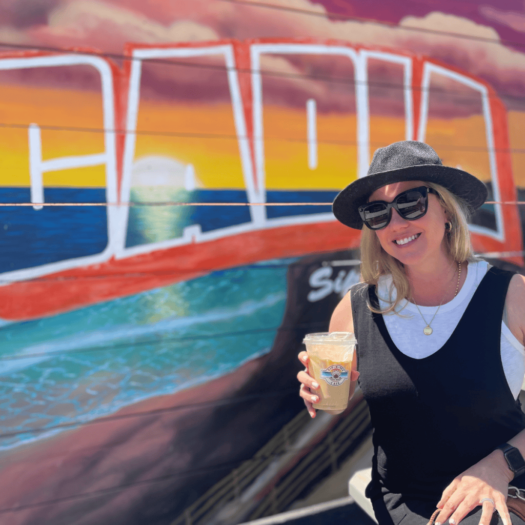 Sitting in front of the colorful mural drinking coffee at Sip-n-Sea- cafe.