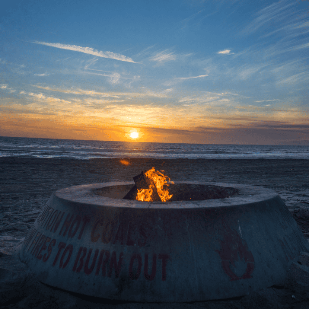Fire pit at a beach campground at sunset.